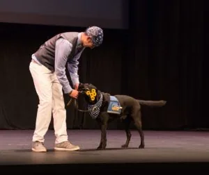 Forrest’s service dog, Toliver brings him flowers during Behind the Label 